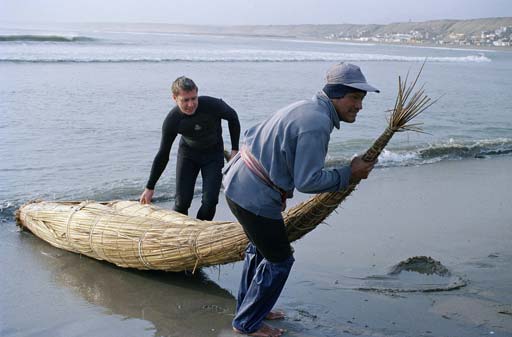 Men dragging reed boat from ocean