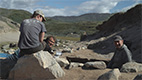 Three men sitting on and around some boulders
